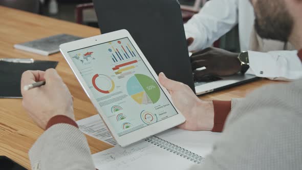 Male Investor Analyzing Business Graphs and Diagrams on Tablet Display