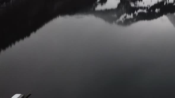 Flying backwards very close to the water and over the ice past a raft on a mountain lake.