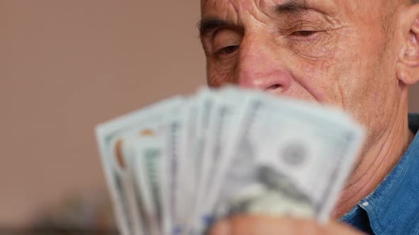 Portrait of Caucasian elderly man counting 100 dollar bills.