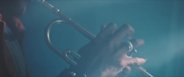 A trumpeter playing in a dark room with neon light and smoke