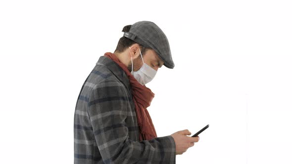 Stylish Man in Medical Mask Walking and Using Smart Phone on White Background