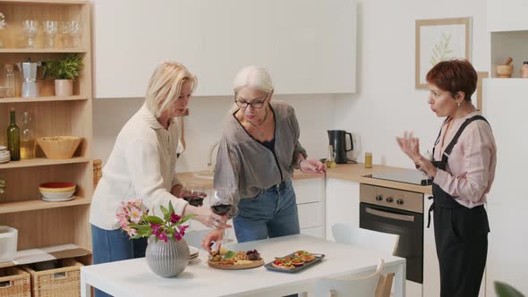 Three Mature Women Serving Dinner Table for Home Gathering