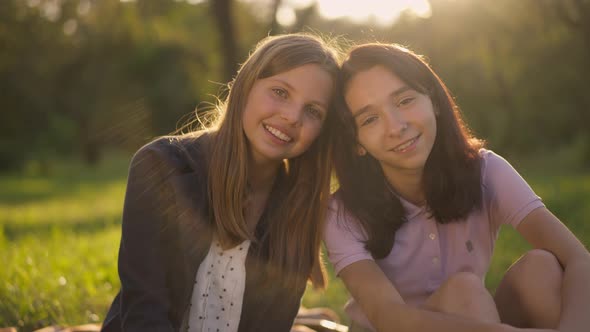 Two Positive Teenage Girls Posing in Sunrays in Slow Motion at Golden Sunset in Park