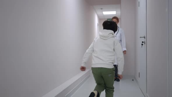 Tracking Shot of Joyful Caucasian Boy Running to Doctor Standing in Hospital Corridor Hugging