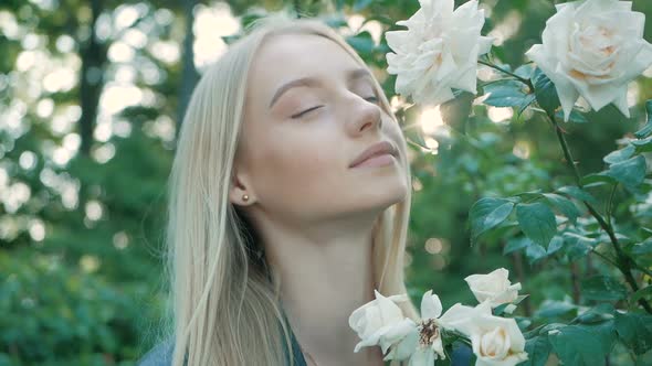 Beautiful happy young woman enjoying smell flowering spring garden