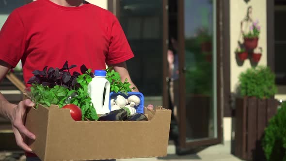 Closeup View of Man Courier is Posing with Box of Fresh Vegetables Outdoors Spbd