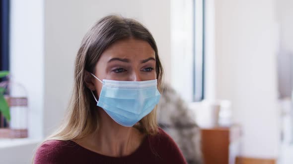 Woman wearing face mask sneezing on her elbow