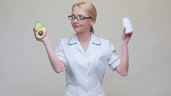 Nutritionist Doctor Holding Organic Avocado Fruit and Jar of Medicine or Vitamin or Omega 3 Capsules