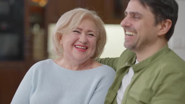 Rack Focus From Cheerful Laughing Senior Mother to Smiling Adult Son Hugging Parent Talking
