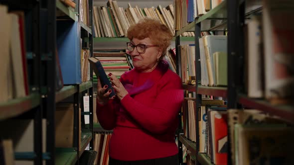 Emotional Elderly Woman in Glasses Found Her Favorite Book on the Shelf Closeup