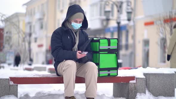 Delivery Man with Green Bagpack Awaiting the Order for Delivery