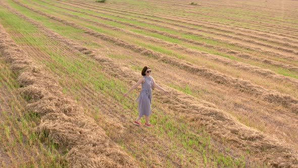 Girl Enjoys Her Walk in the Field. Girl Have Fun and Throws Hay Up