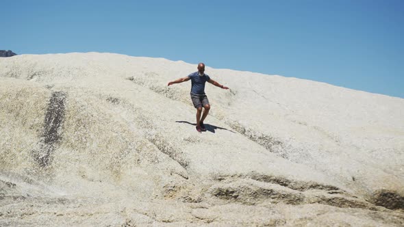 Senior african american man exercising running on rocks by the sea