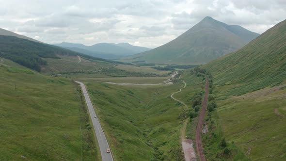 Stationary aerial shot of cars driving through the Scottish highlands