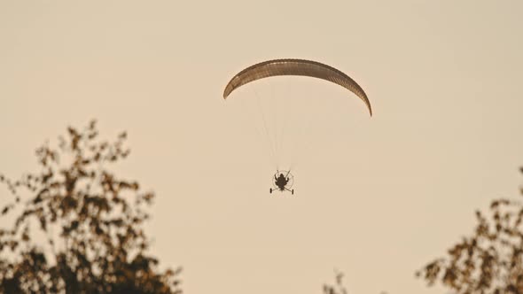 Paramotor Flying in Air Against Sunset Sky