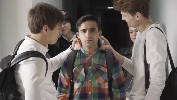 Group of Aggressive Teenagers Mocking Nerd Sad Boy in High School Corridor
