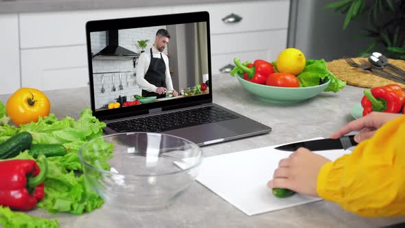 Woman in Kitchen Study Online Video Call Laptop Listen Chef Slices Cucumber