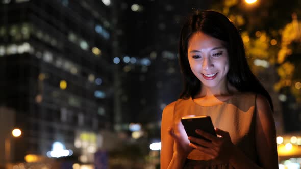 Woman using mobile phone in city at night 