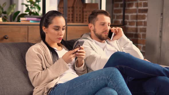 Couple Sitting on the Couch While Communicating with Friends