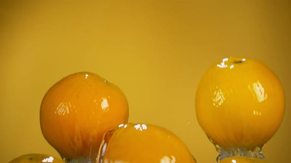 Group of Ripe Oranges are Bouncing with Water Splashes on the Yellow Background