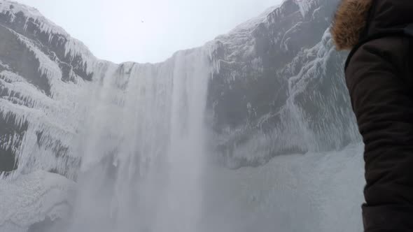 Tourist Walking Up To Reveal The Large Skogafoss Waterfall In Iceland During Winter 1
