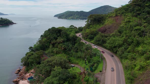 Beautiful landscape on coast of Ubatuba, traffic on coastal road, Brazil. Aerial proximity flight ne