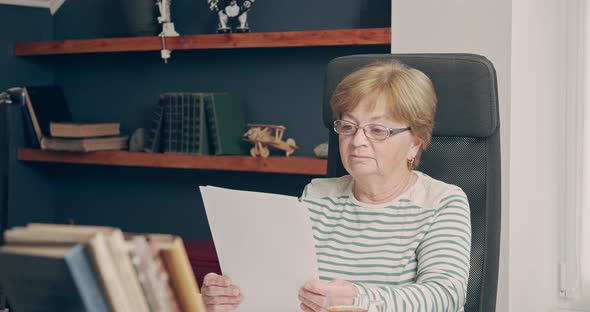 Older Woman Indoors Work with a Paper Documents