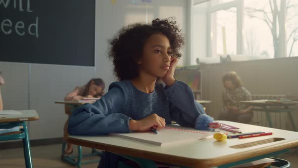 Pensive Student Sitting at School Desk in Class