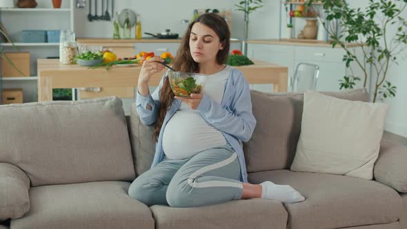 Pregnant Woman With Great Pleasure Eating Vegetable Salad on the Couch