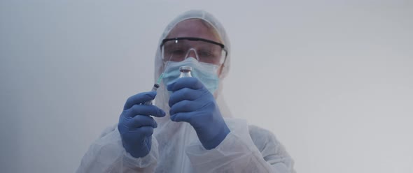 Woman holding up and lowering vaccine bottle and syringe