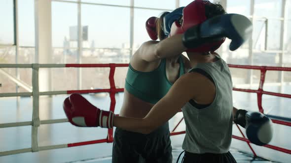 Slow Motion of Beautiful Young Women Wearing Helmets and Gloves Hugging After Match in Modern Gym