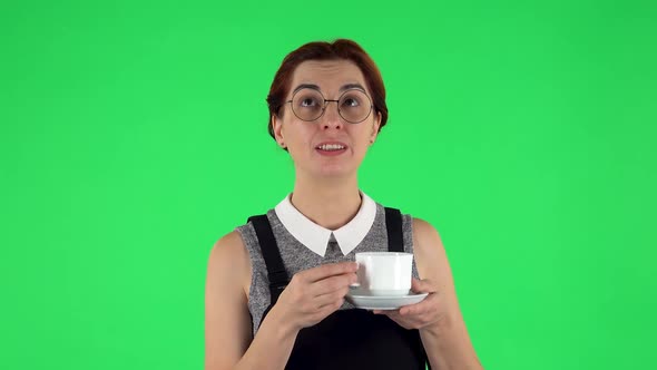 Portrait of Funny Girl in Round Glasses Is Enjoying Coffee. Green Screen