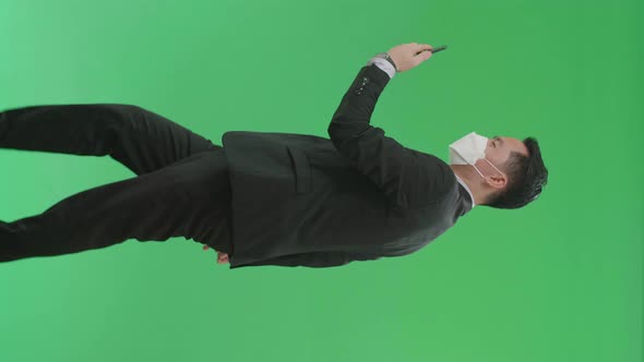 Business Man Having Video Call On Mobile Phone While Walking On Green Screen, Wear Medical Mask