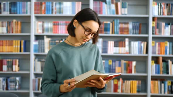 A Young Female Millennial Student Writes an Assignment in Her Notebook While Standing in a Public