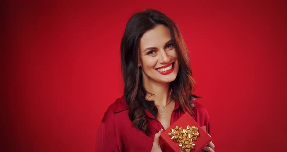 Beautiful Woman Enjoys a Valentine's Gift on a Red Background
