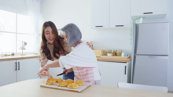 Asian lovely family, young beautiful daughter hugging and look to old mother cook in kitchen.