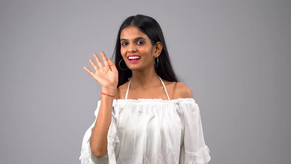 Happy Indian girl waving her hand and saying Hi