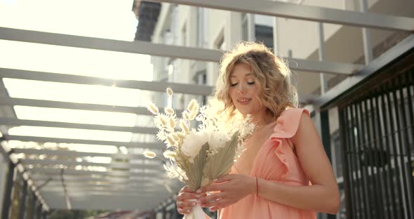 Smiling Woman with Curly Hair Holding Bunch of Flowers