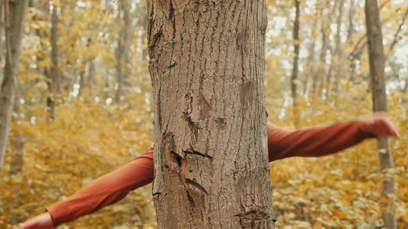 Girl Hugging Tree Trunk in Autumn Forest