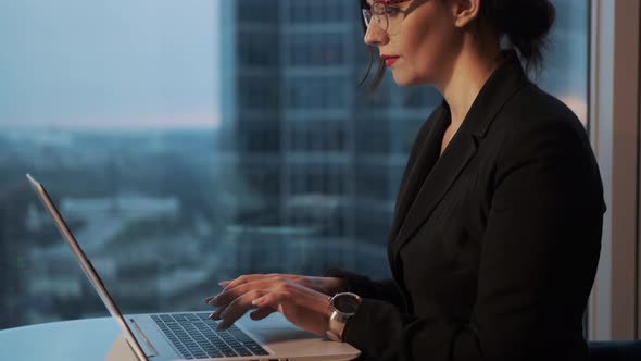 Portrait of Business Woman with Glasses in the Office. Girl Sitting at the Table and Working on a