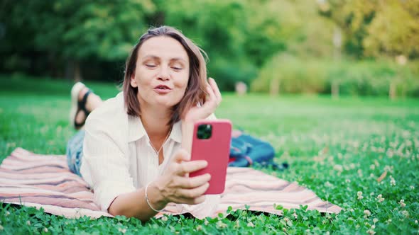 Beautiful Adult Woman Taking a Video Call on Her Smartphone at the Park