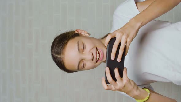 Vertical Video of a Teenager Girl Having Fun While Playing Video Game Touching Smartphone Screen
