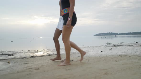 Side View Interracial Couple Walking on an Exotic Island Beach Along the Sea at Sunset Matching Leg