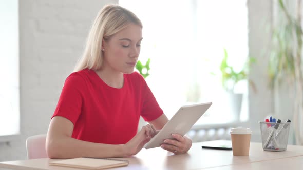 Young Blonde Woman using Tablet while Sitting in Office