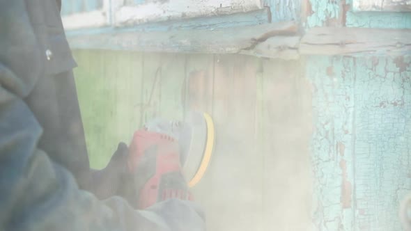 Close-up of a man grinding an old wooden surface with an orbital sander. Slow motion