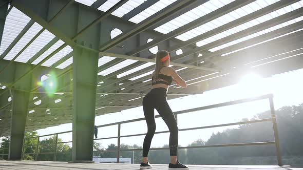 Beautiful Slim Sporty Young Woman in Sportswear Doing Squat Exercises in the Open air Ground