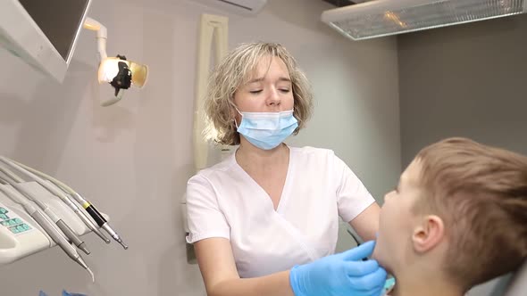 A little boy treats his teeth, two dentists examine the child's teeth