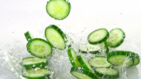 Super Slow Motion Shot of Cucumber Slices Falling Into Water on White Background at 1000Fps