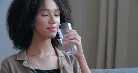Close Up of Young African American Woman Quenches Her Thirst, Holds Glass Cool Warm Water, Drinks