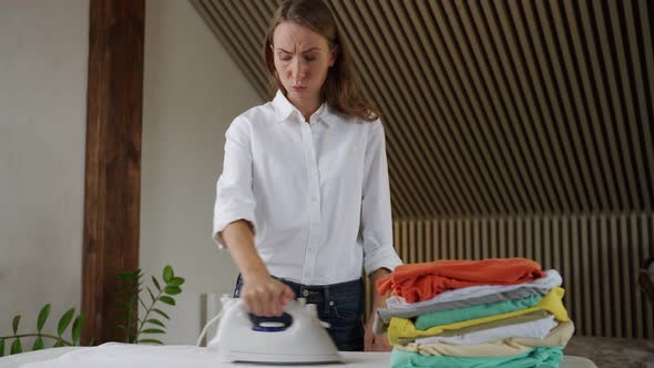 Young Tired Woman with Clean Laundry at Ironing Board Indoors